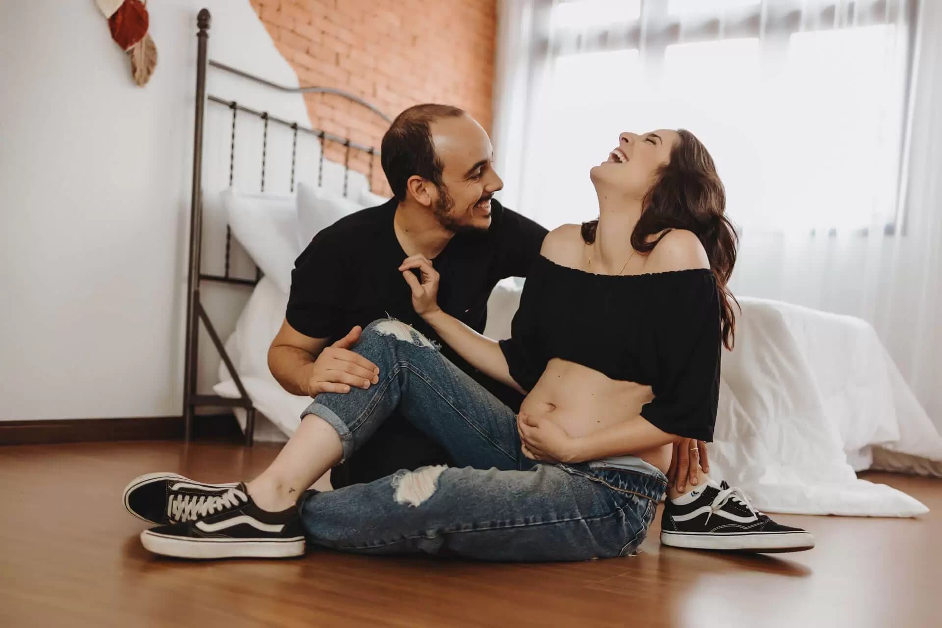 Casal sorrindo enfrente a cama